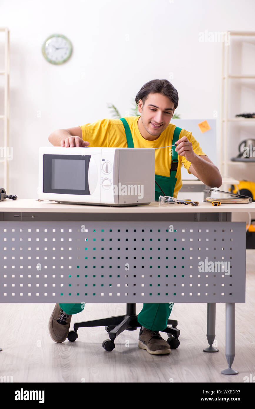 Young repairman repairing microwave in service centre Stock Photo