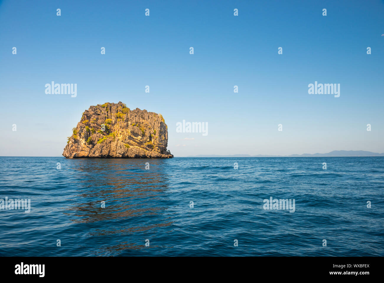 Rocky tropical island in blue sea Stock Photo