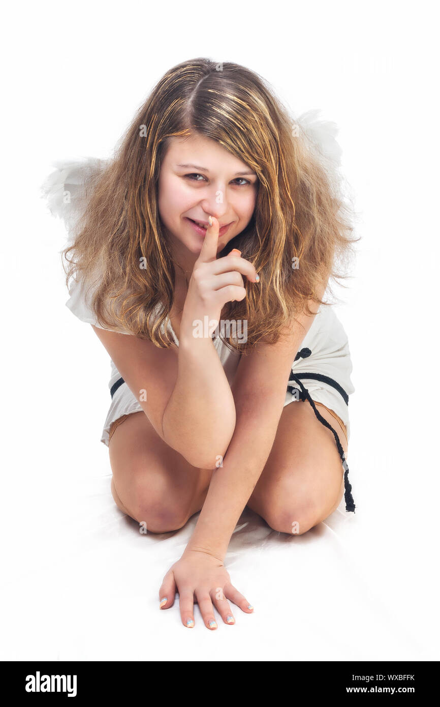 smiling christmas angel with golden hair and wings holding finger on lips on white background Stock Photo