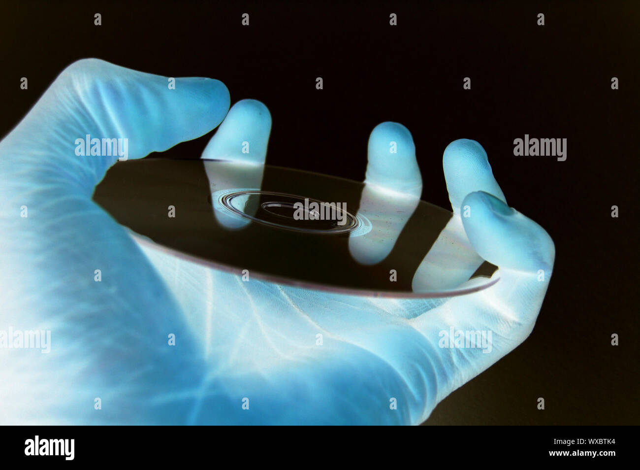 This is an image of a hand hold a data cd in a (dark technology room ...