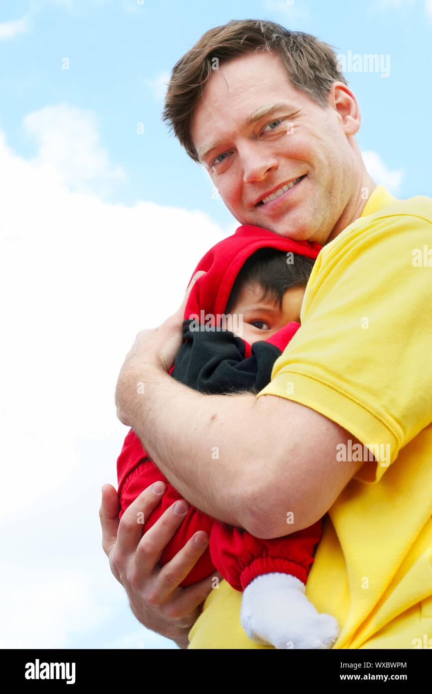 Baby cuddled safely in dad's arms Stock Photo