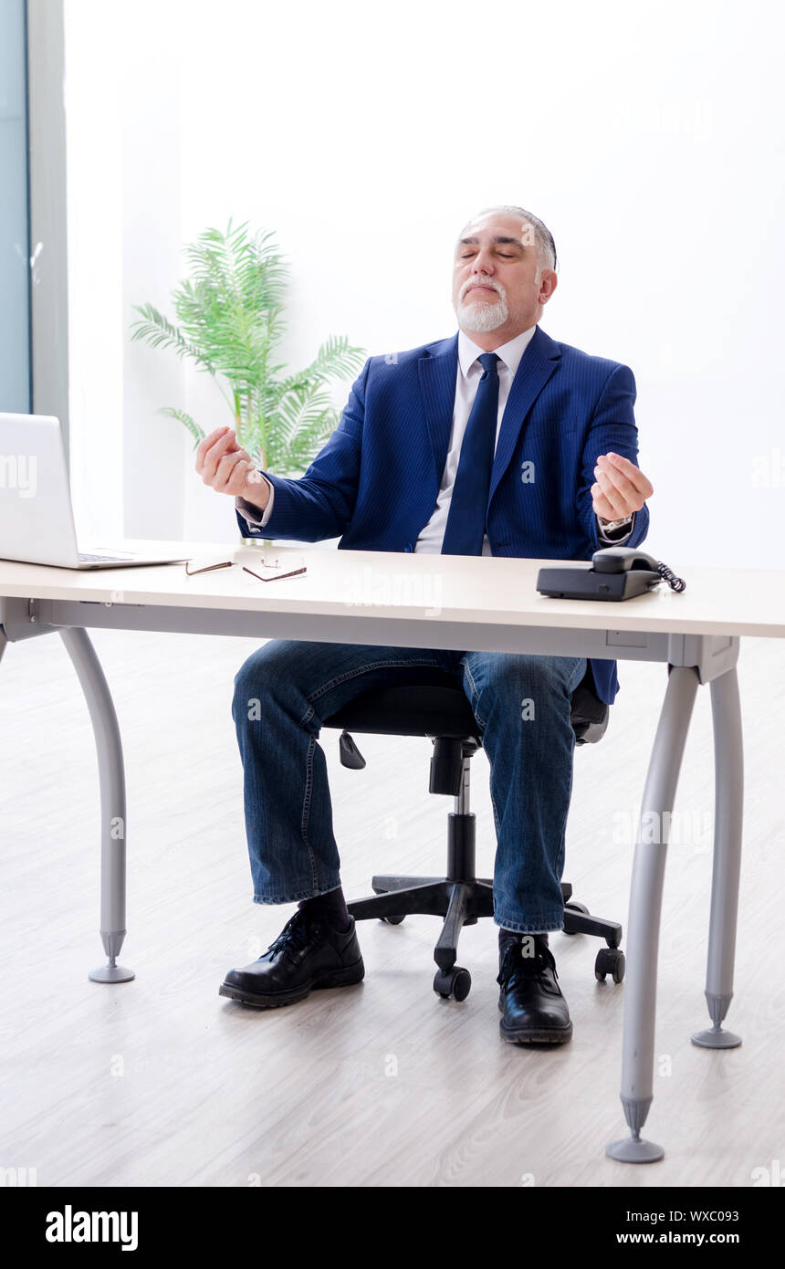 Aged businessman doing yoga exercises in the office Stock Photo - Alamy