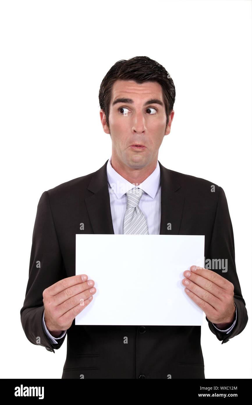 A businessman presenting a poster with a weird facial expression. Stock Photo
