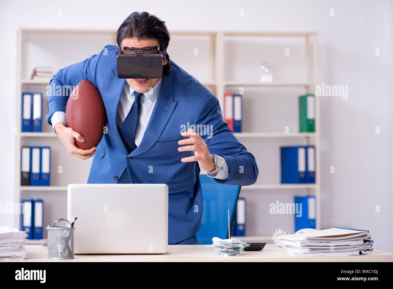 Young handsome businessman playing rugby with virtual glasses Stock Photo