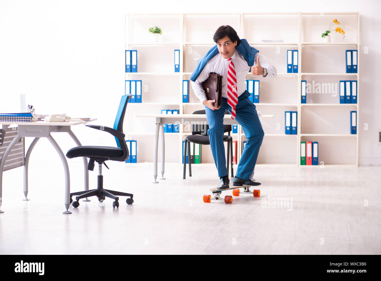 Young handsome businessman with longboard in the office Stock Photo - Alamy