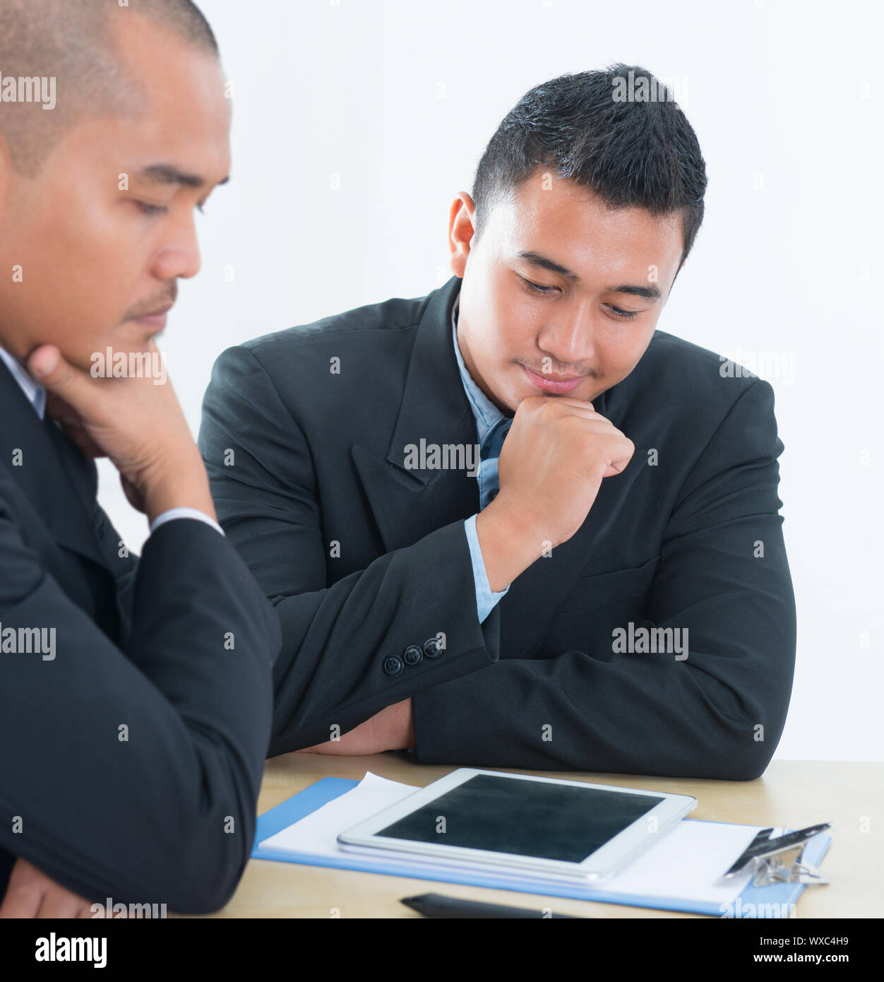 Southeast Asian business people discussing, sitting in office. Stock Photo