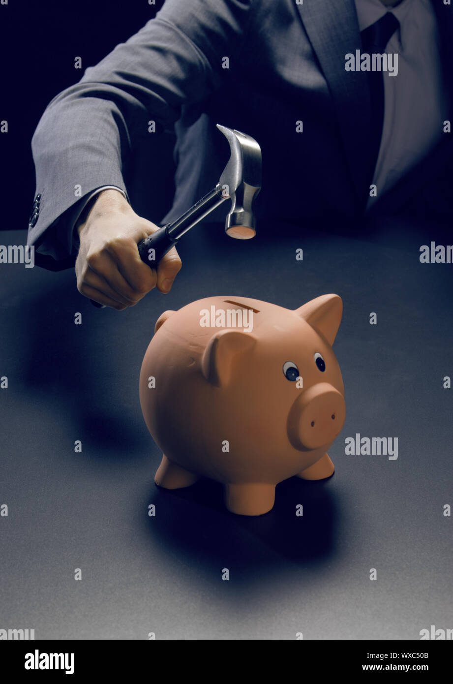 Hammer about to smash piggy bank Stock Photo - Alamy