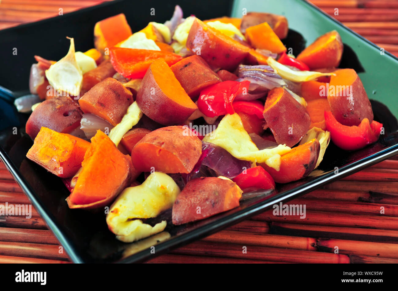 Vegetarian dish of roasted yams with cheese and peppers Stock Photo