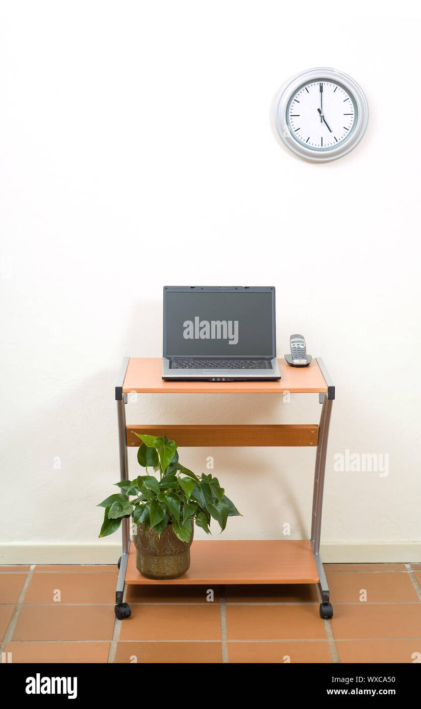 Office Desk With Laptop And Phone Potplant Under Desk Stock Photo
