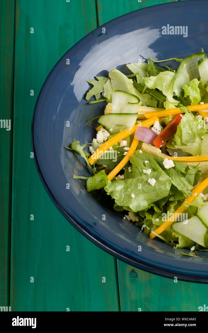 Green salad in blue bowl on wooden table Stock Photo - Alamy