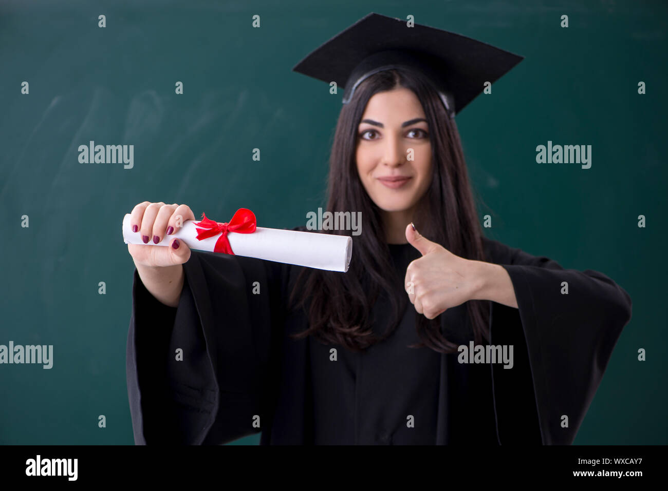 Female graduate student in front of green board Stock Photo - Alamy