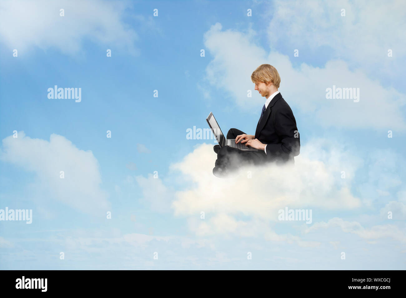 Young business man sitting on clouds and using a laptop Stock Photo - Alamy