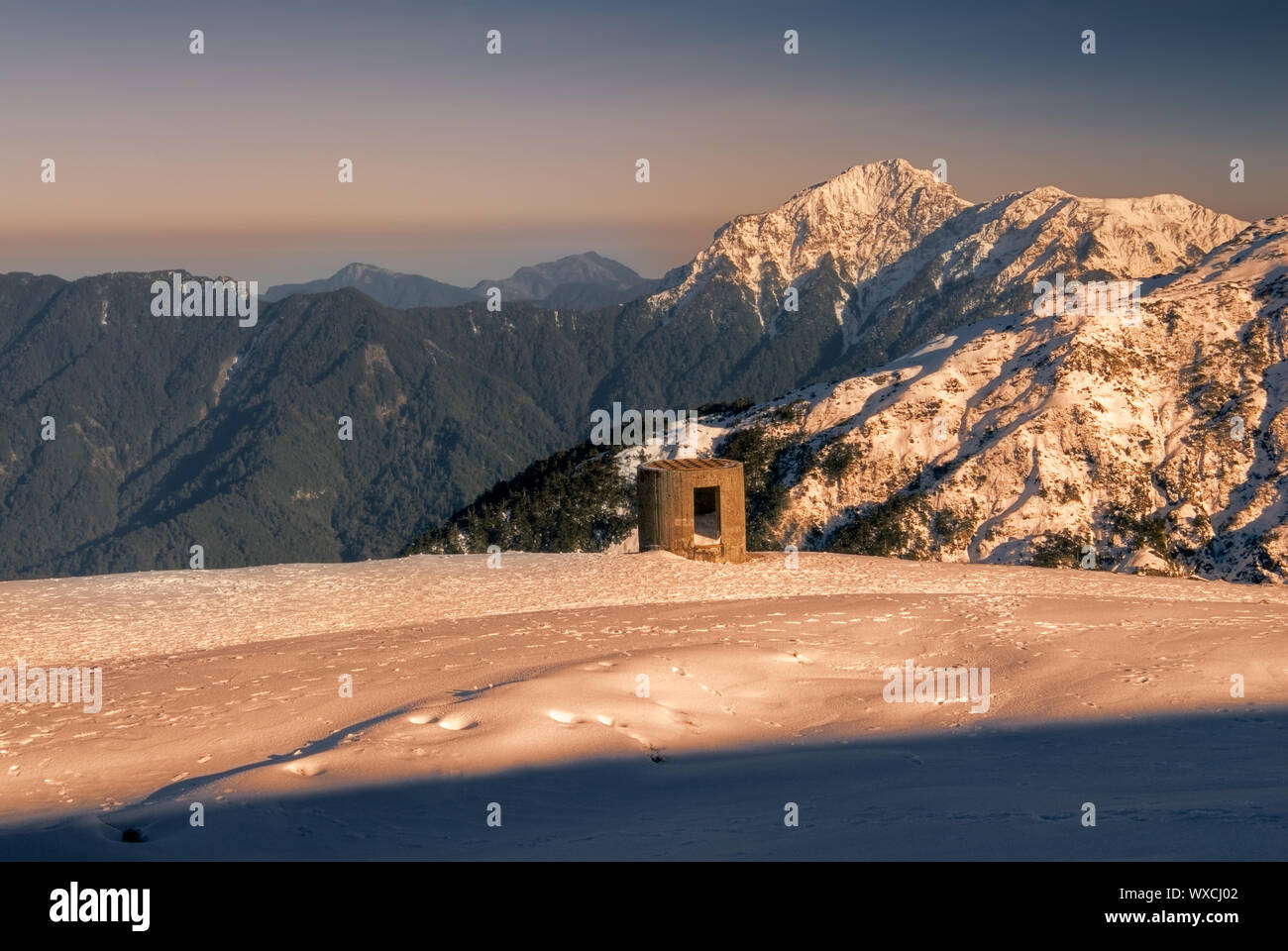 Beauty of snow mountain with blockhouse in yellow sunset Stock Photo