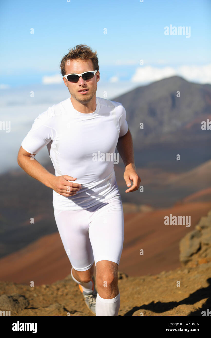 Good-looking athletic young man running cross-country through mountainous terrain training for a sports event Stock Photo