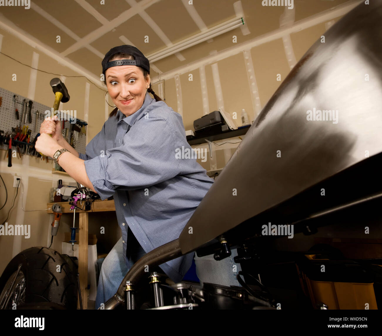 Hispanic woman swinging a sledgehammer at a motorcycle Stock Photo Alamy