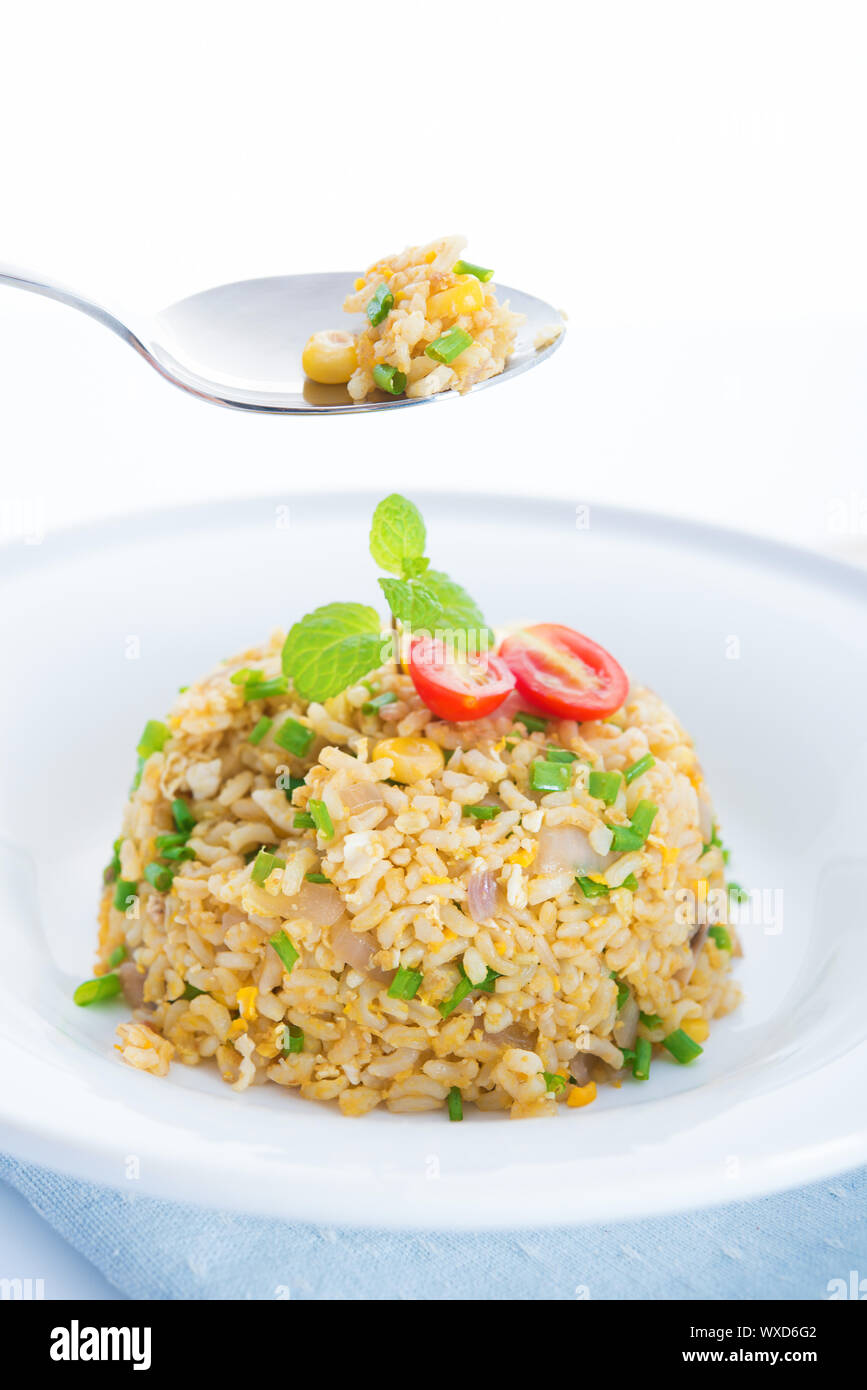 Chinese egg fried rice on dining table. Focus on the spoon. Stock Photo