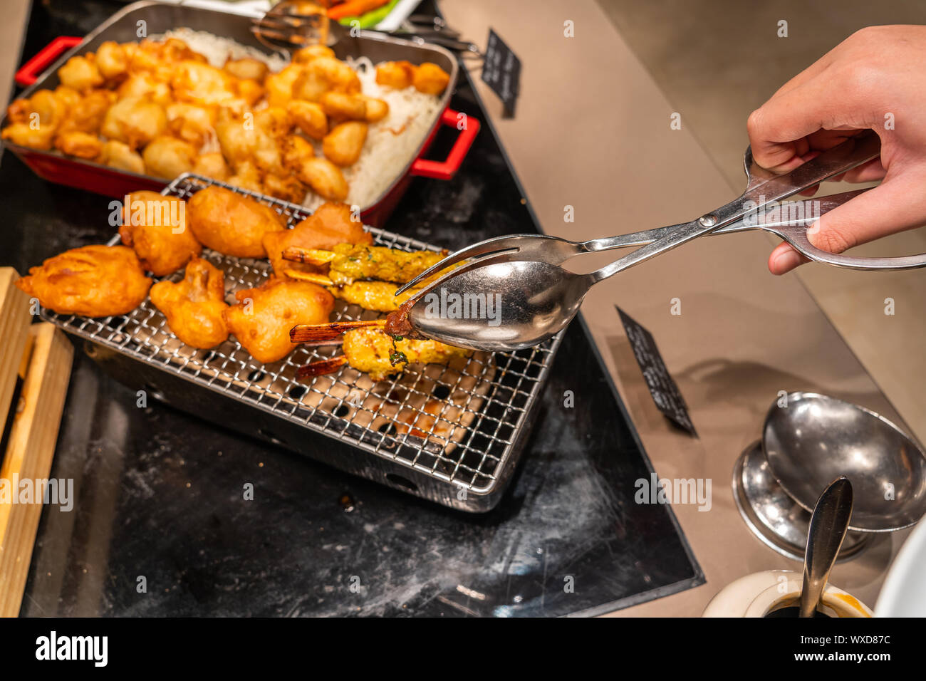 Human hand picking fried chicken stick in buffet restaurant Stock Photo