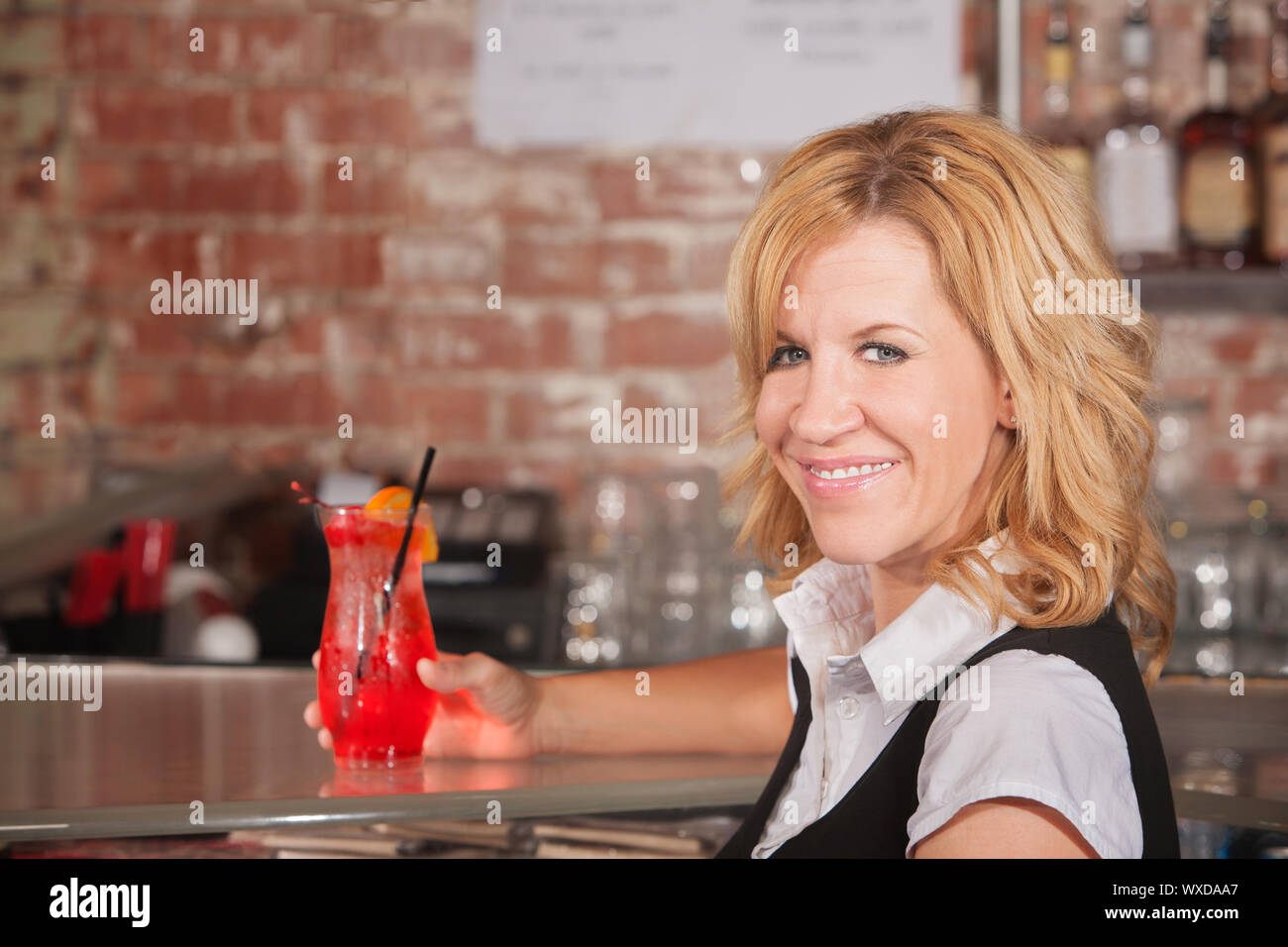 Happy hostess with alcoholic beverage glass in bar Stock Photo Alamy