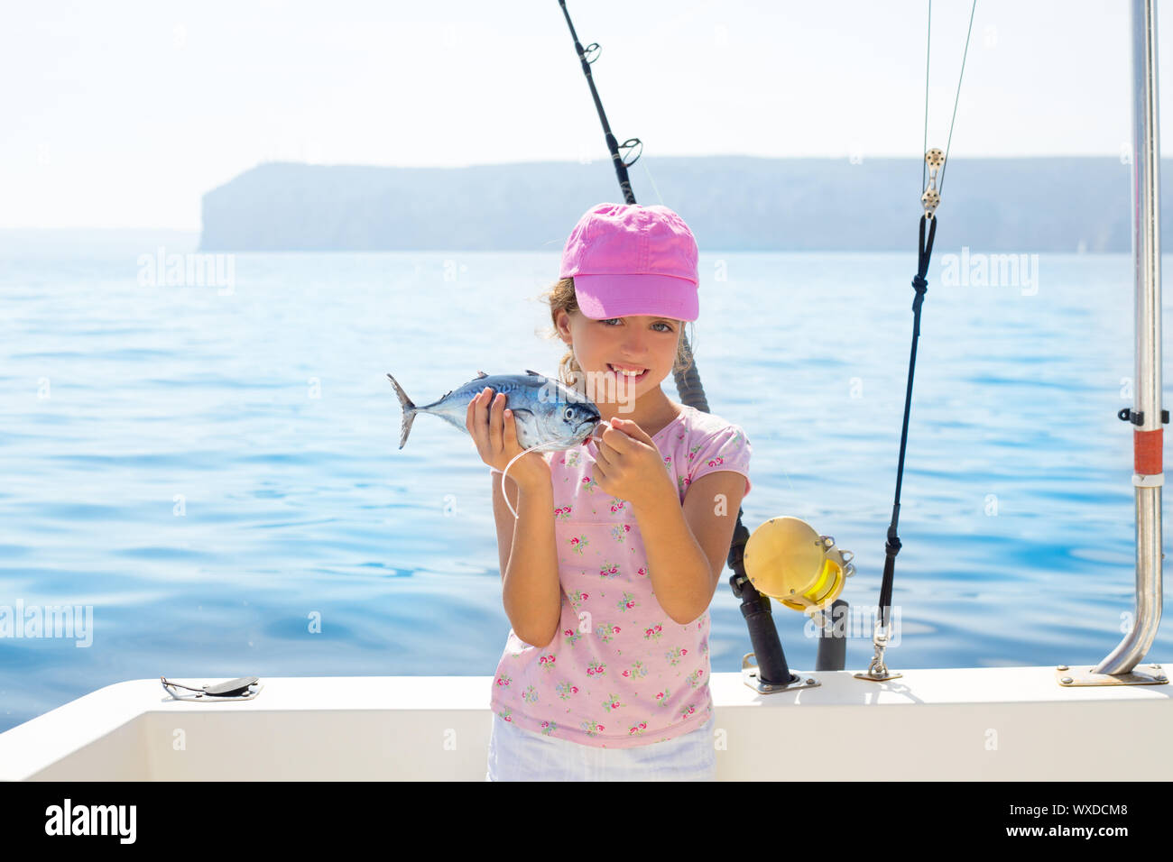 child little girl fishing in boat holding little tunny tuna fish