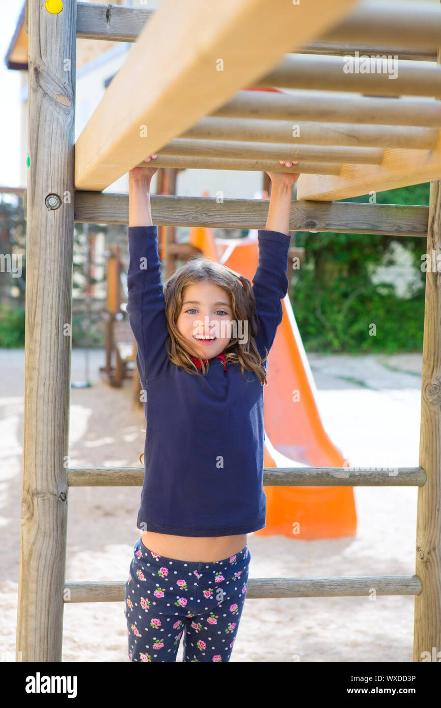 kid girl playing in playground hanging from wood bars smiling happy ...