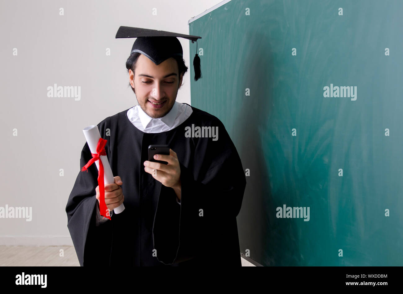 Graduate Front Use Graduate student in front of green board Stock Photo - Alamy