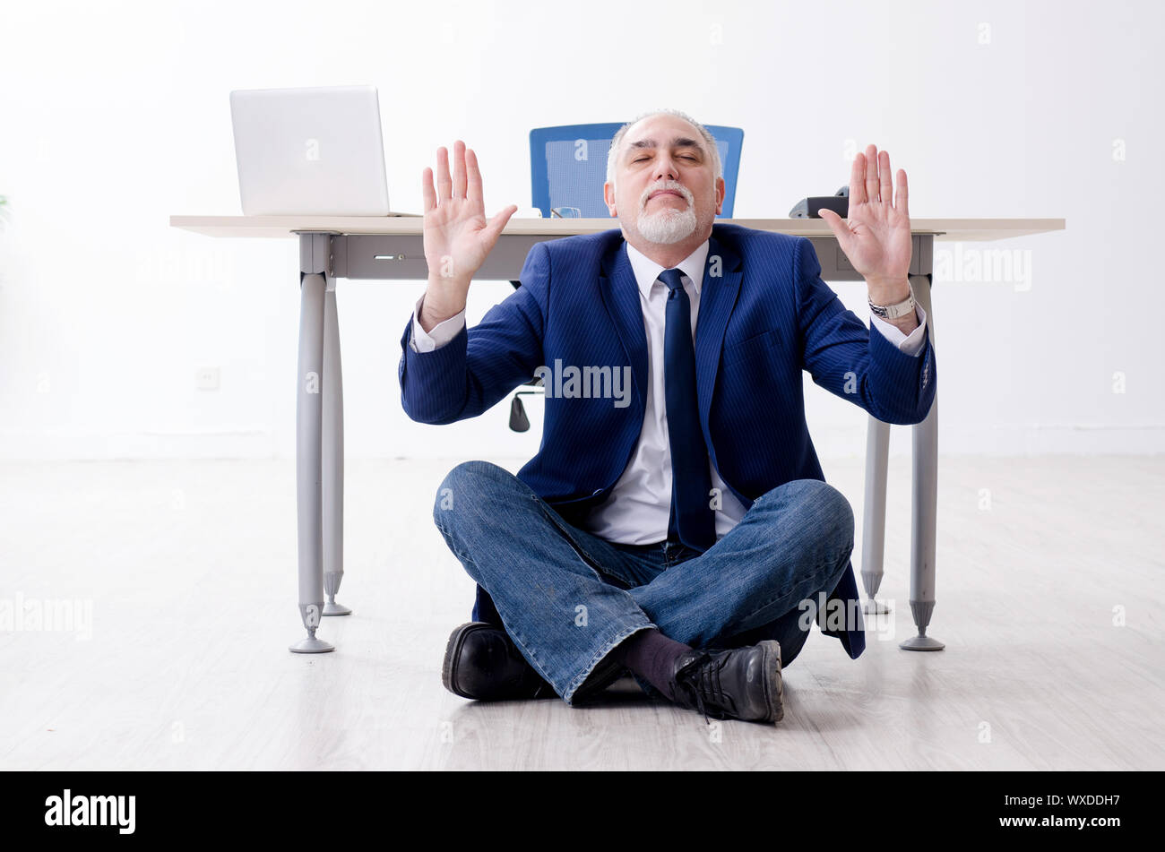 Aged businessman doing yoga exercises in the office Stock Photo - Alamy