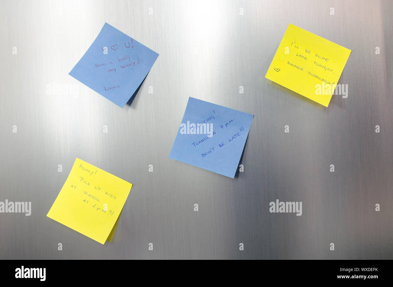 Reminder sticky notes with handwritten text hanging on a stainless fridge. Stock Photo