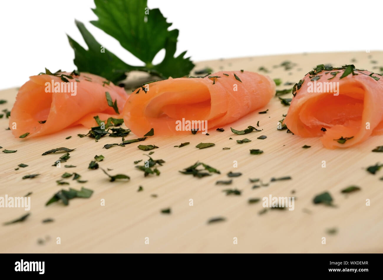 Smoked salmon on a wooden cutting board, garnished with herbs and ...