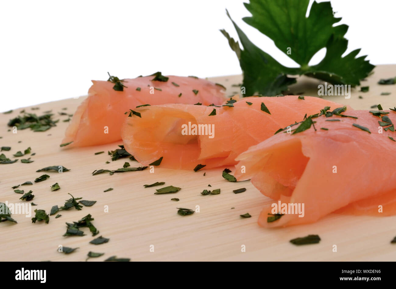Smoked salmon on a wooden cutting board, garnished with herbs and ...