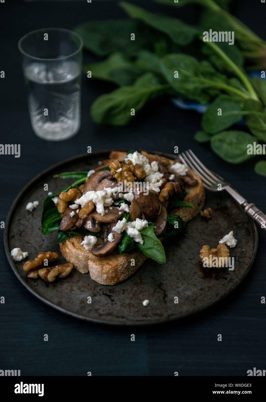 moody food photography of mushrooms, feta and spinach on toast Stock Photo