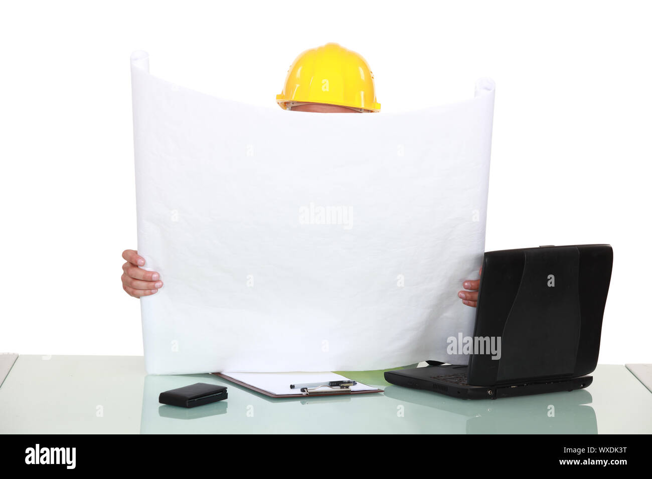 Architect sat at desk reading plans Stock Photo