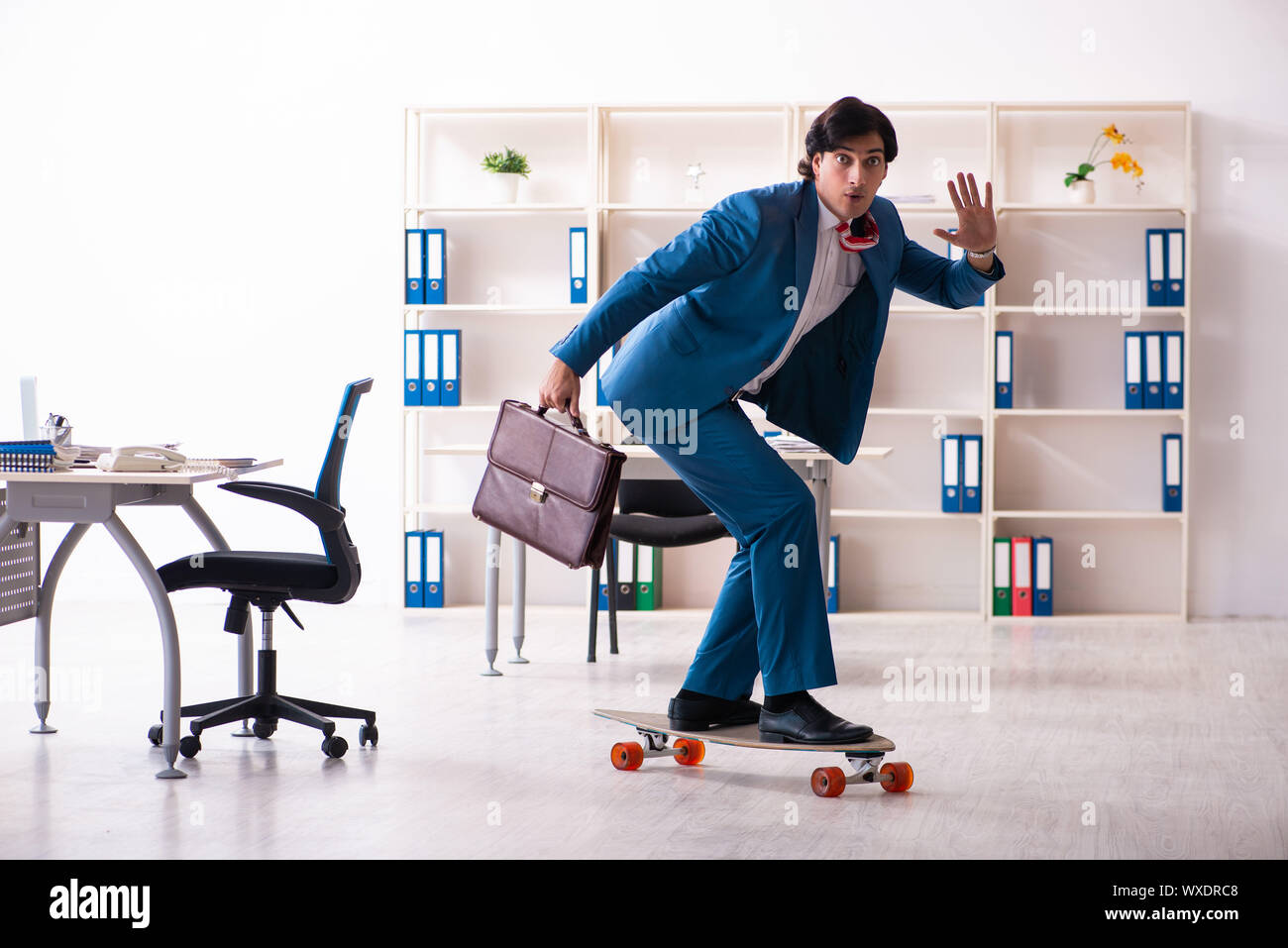 Young handsome businessman with longboard in the office Stock Photo - Alamy