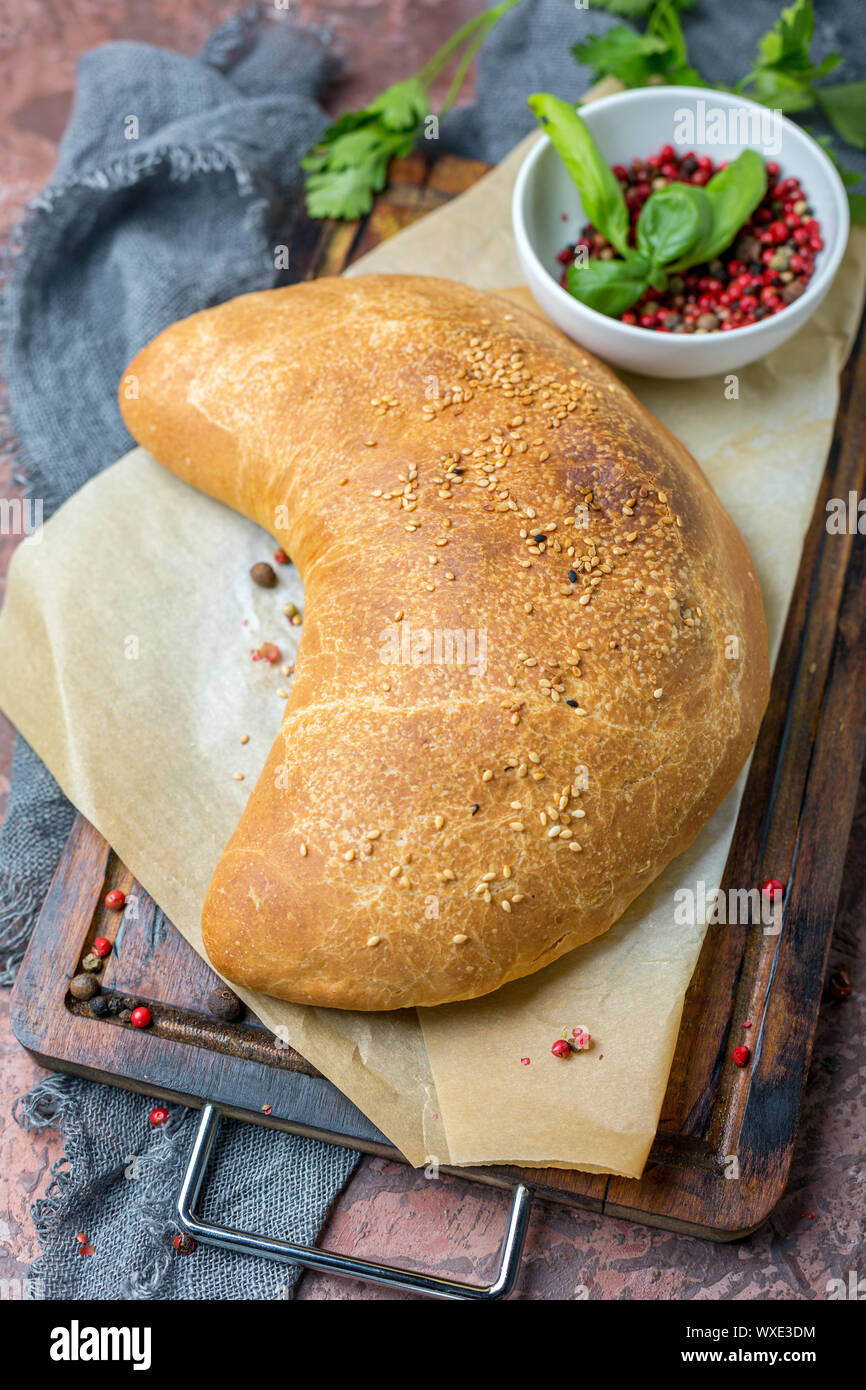 Traditional pizza calzone on a wooden board. Stock Photo