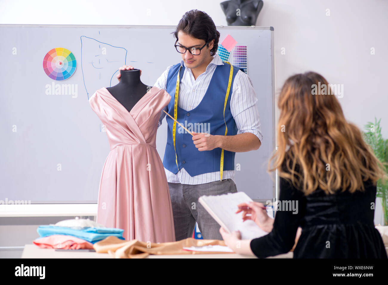 Young male tailor teaching female student Stock Photo - Alamy