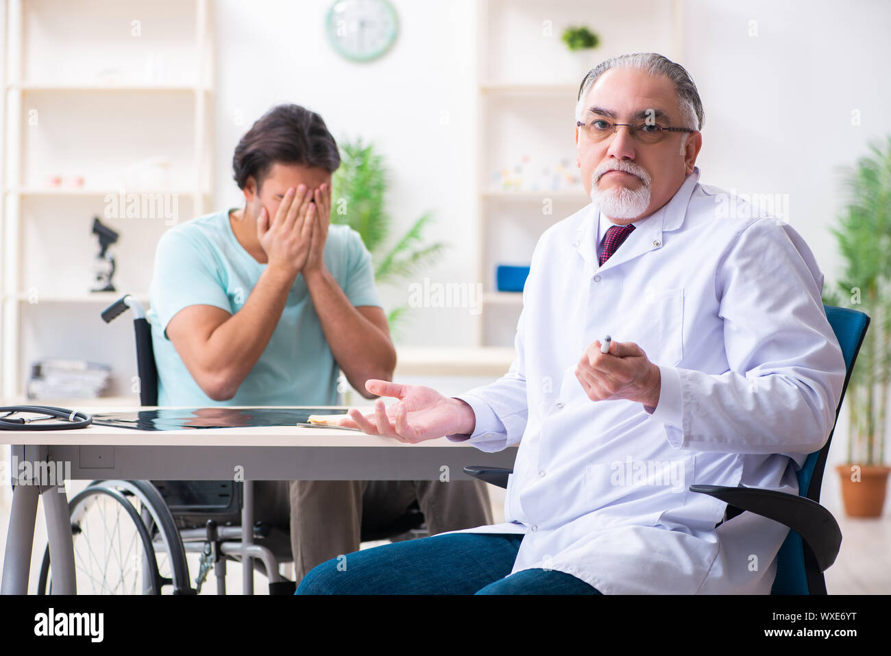 Male patient in wheel-chair visiting old doctor Stock Photo