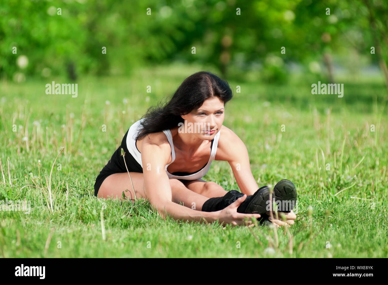 Athletic woman stretching her leg at the park Stock Photo - Alamy