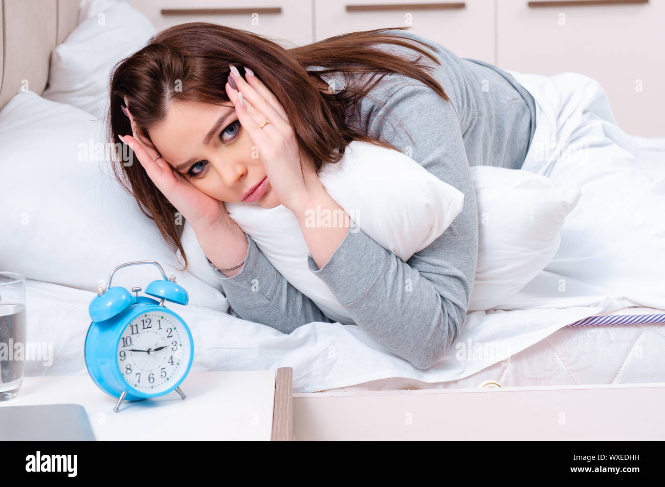 Young woman lying on the bed in time management concept Stock Photo Alamy