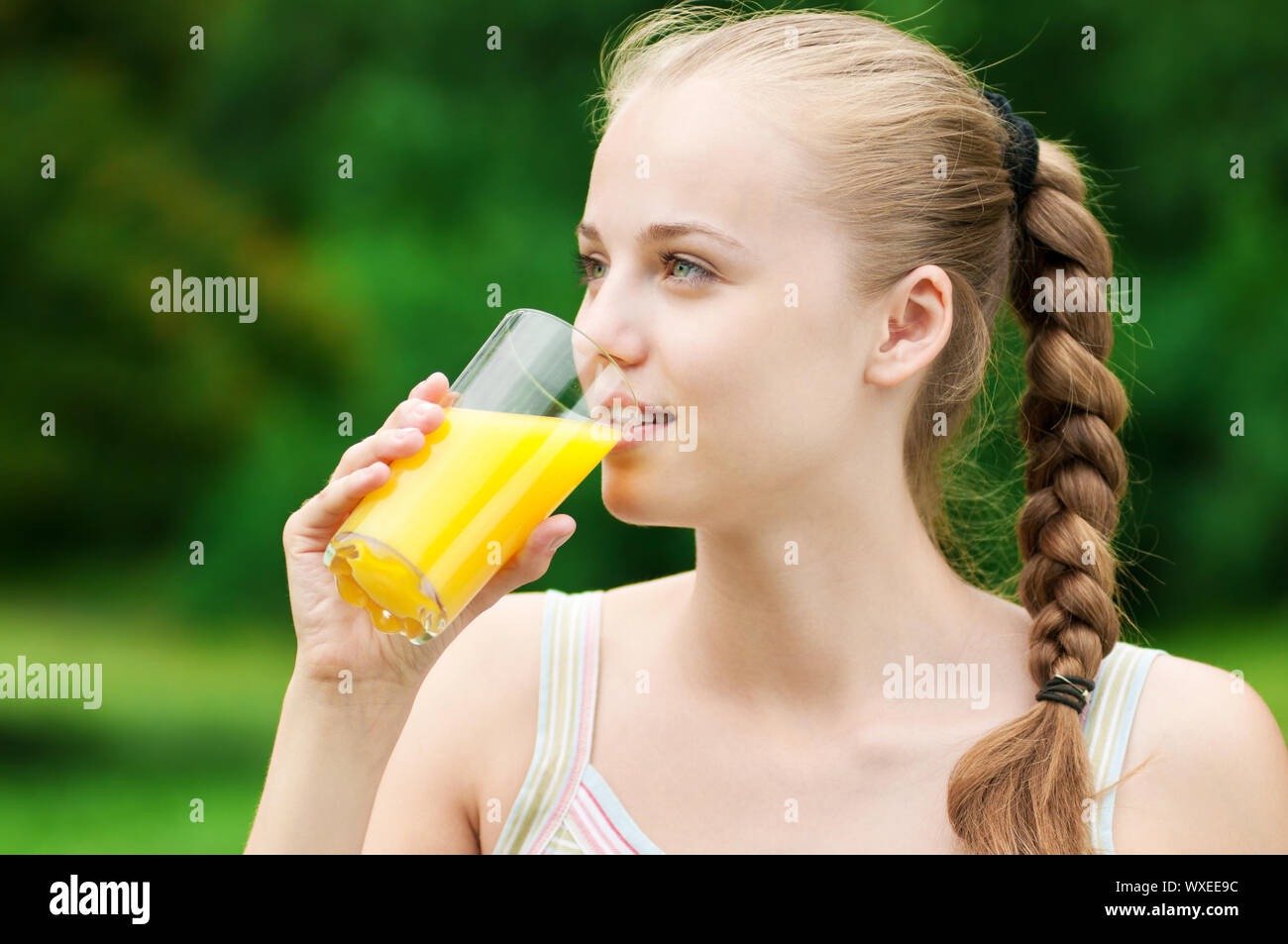 Young woman drinking orange juice after outdoor fitness exercise Stock