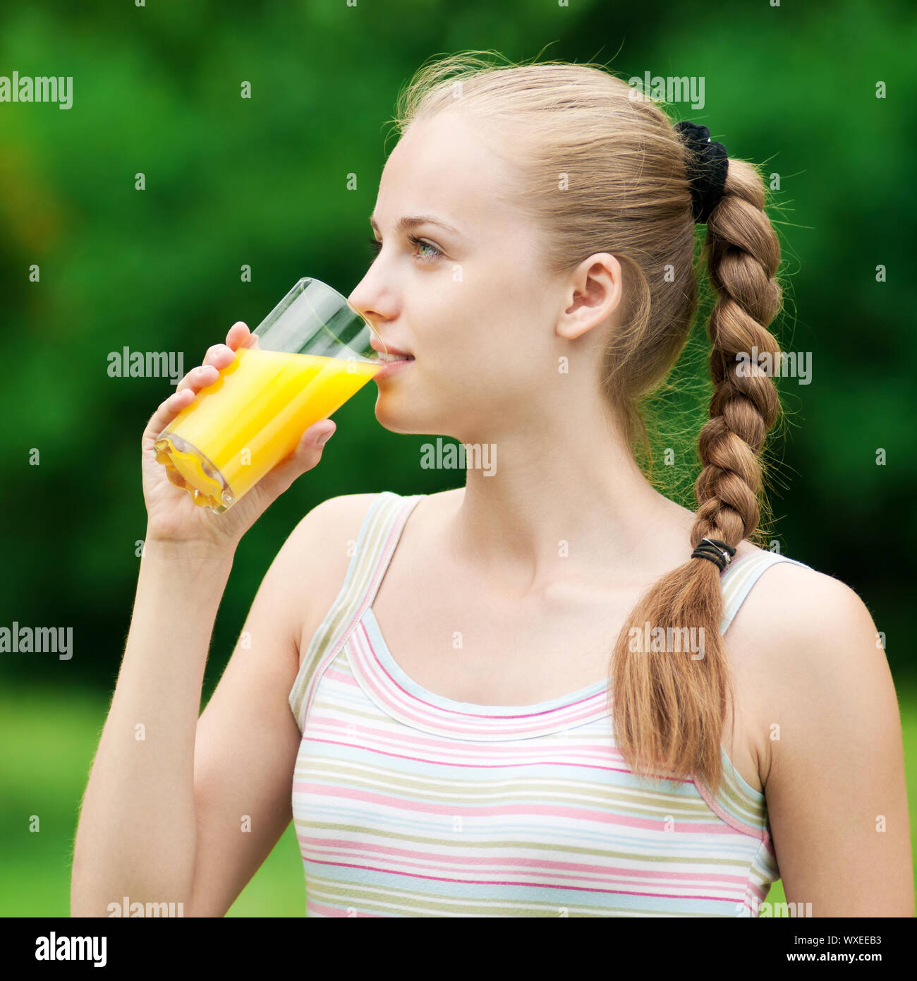 Young woman drinking orange juice after outdoor fitness exercise Stock
