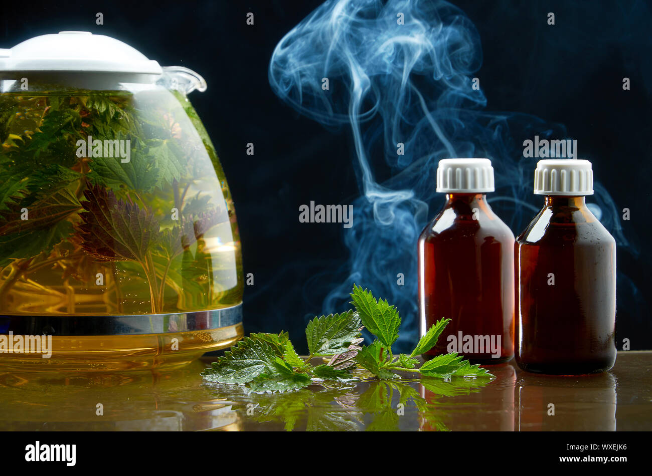 Tea teapot of fresh nettle and nettle leaves in a medical environment on a black background Stock Photo