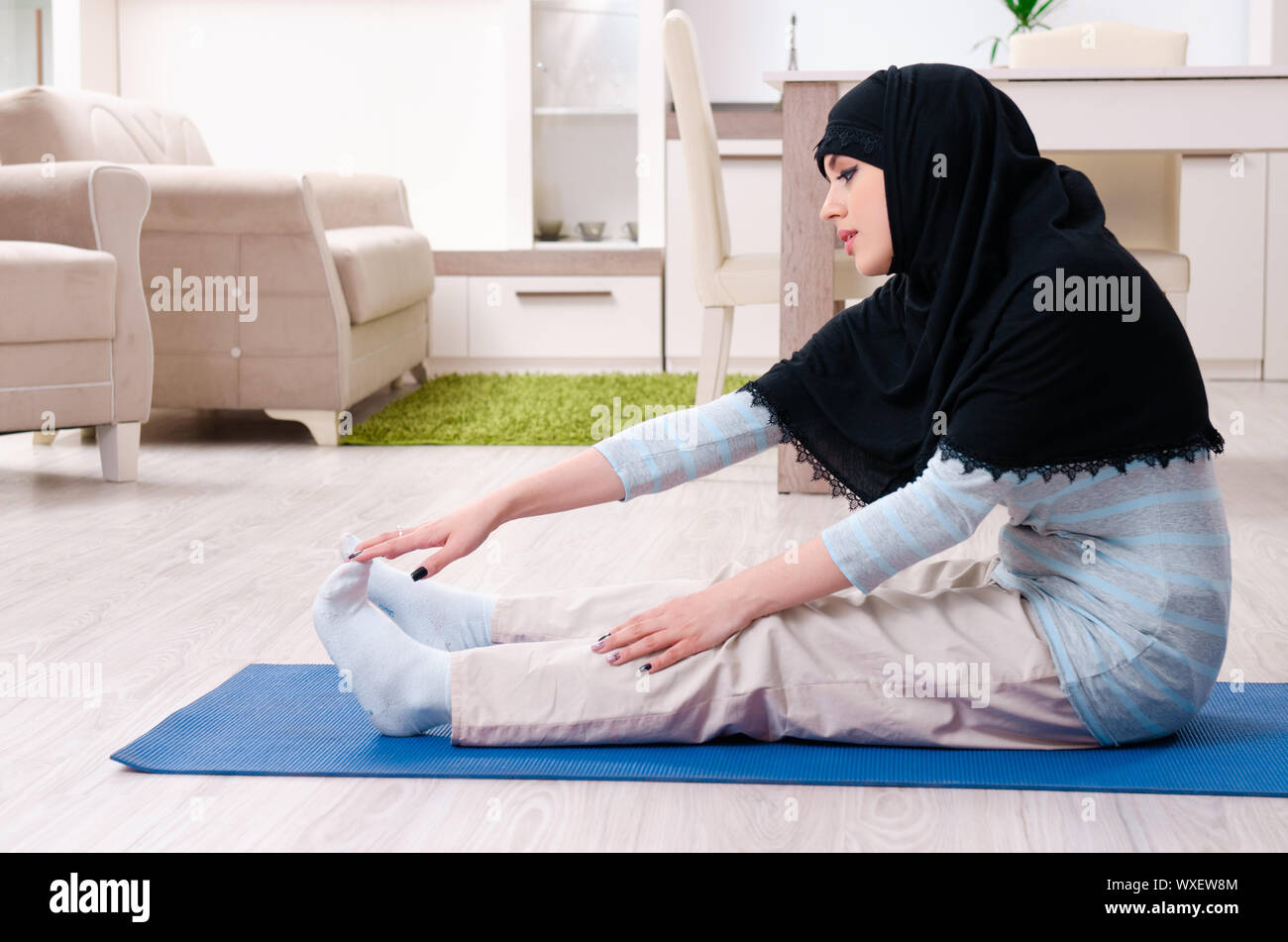 Young woman in hijab doing exercises at home Stock Photo - Alamy