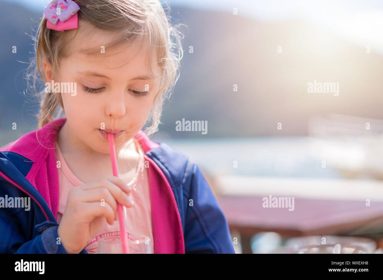 Cute little girl drinking fruit juice using straw Stock Photo