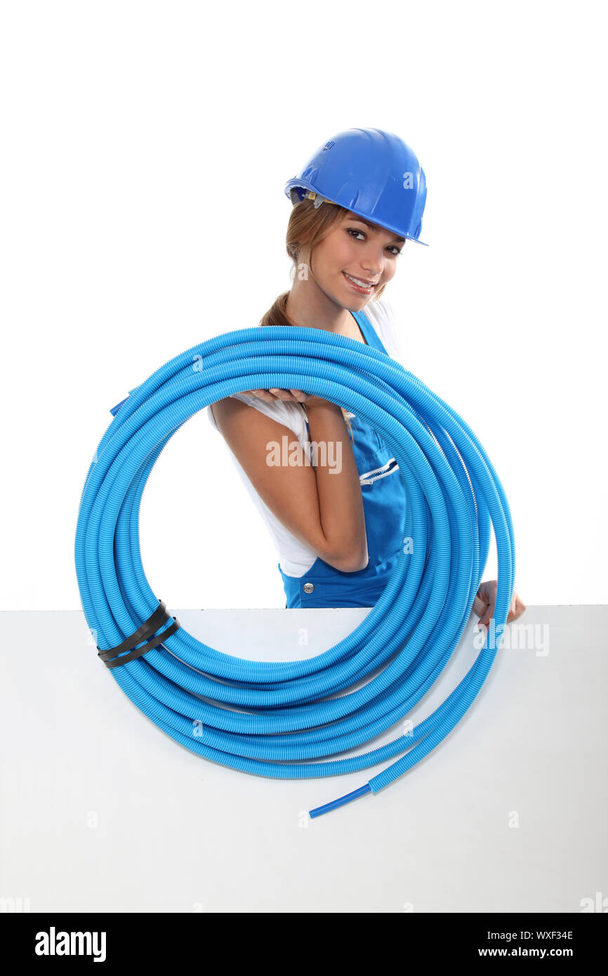 portrait of cute female plumber carrying hose with copyspace against studio background Stock Photo