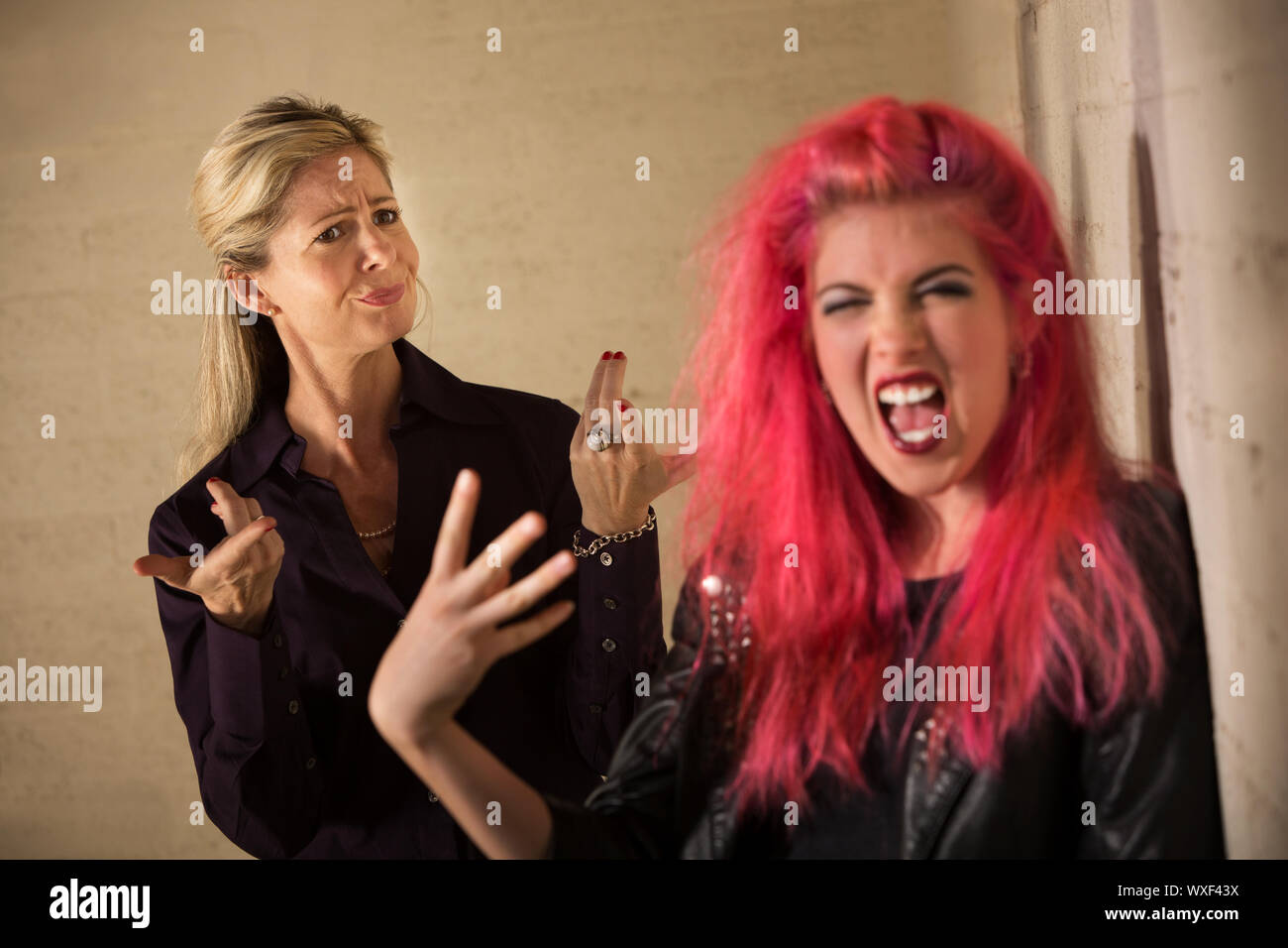 Loud teenage girl in pink hair with disapproving mother Stock Photo