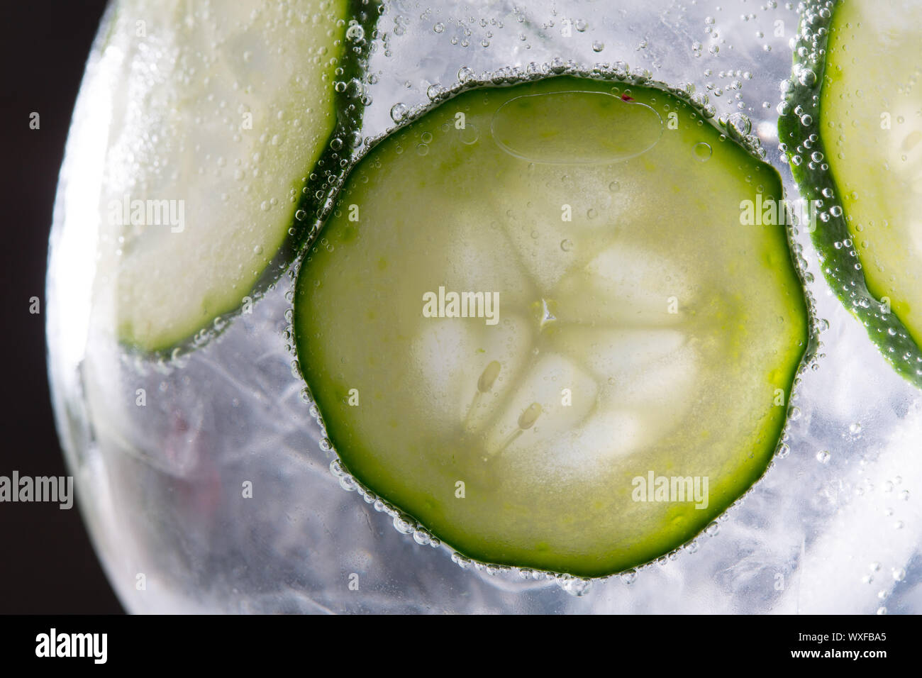 Gin tonic cocktail with cucumber and ice macro closeup on black Stock