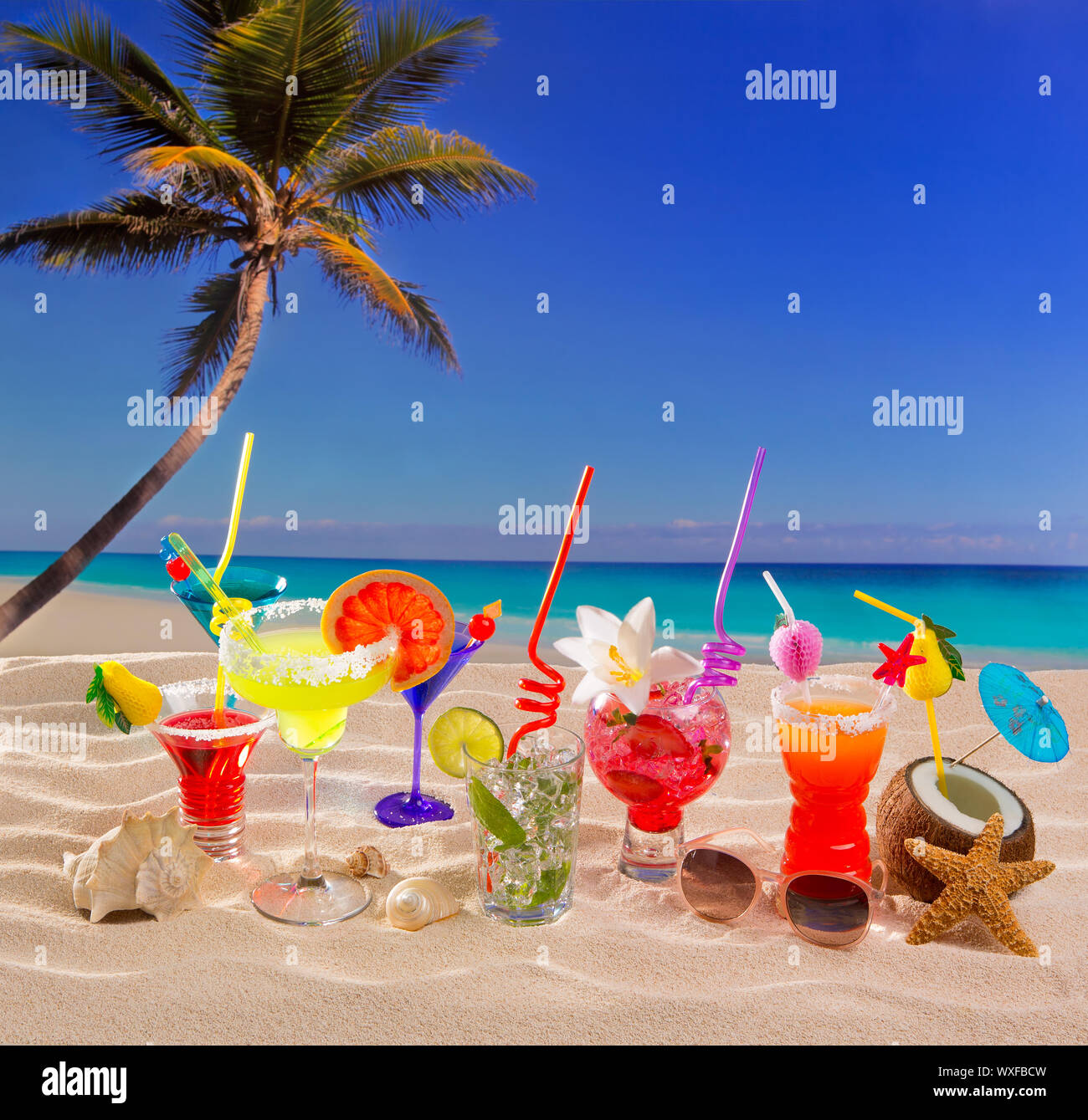 Colorful tropical cocktails at beach on white sand and palm tree Stock Photo