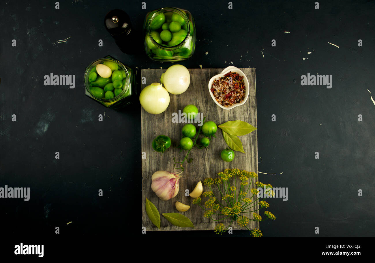 VEGETABLES TOMATOES AND SPICES ON THE BOARD. ONIONS GARLIC TOMATOES DILL SPICES ON GREY WOODEN BOARD ON A RAISED STONE SURFACE. Stock Photo