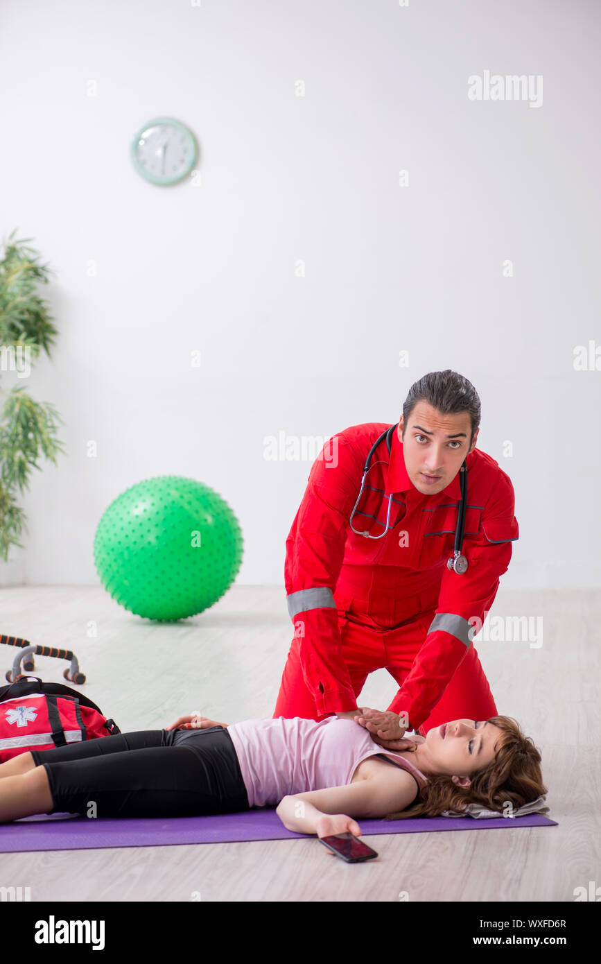 Paramedic in red visiting young woman in gym Stock Photo