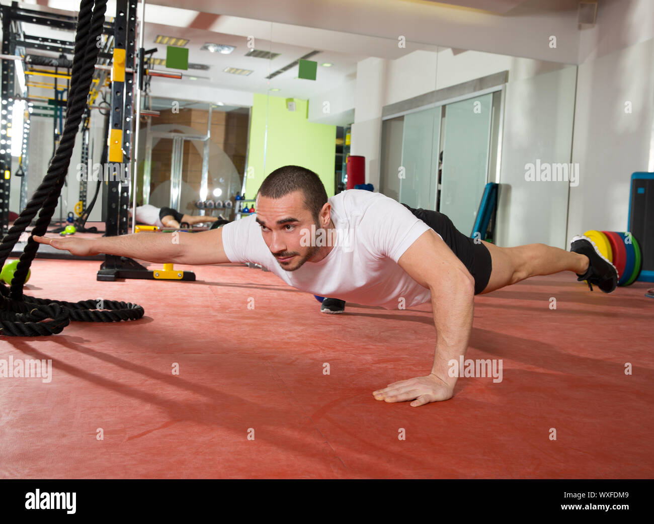 Crossfit fitness man balance push ups with one leg and arm up exercise at gym workout Stock Photo