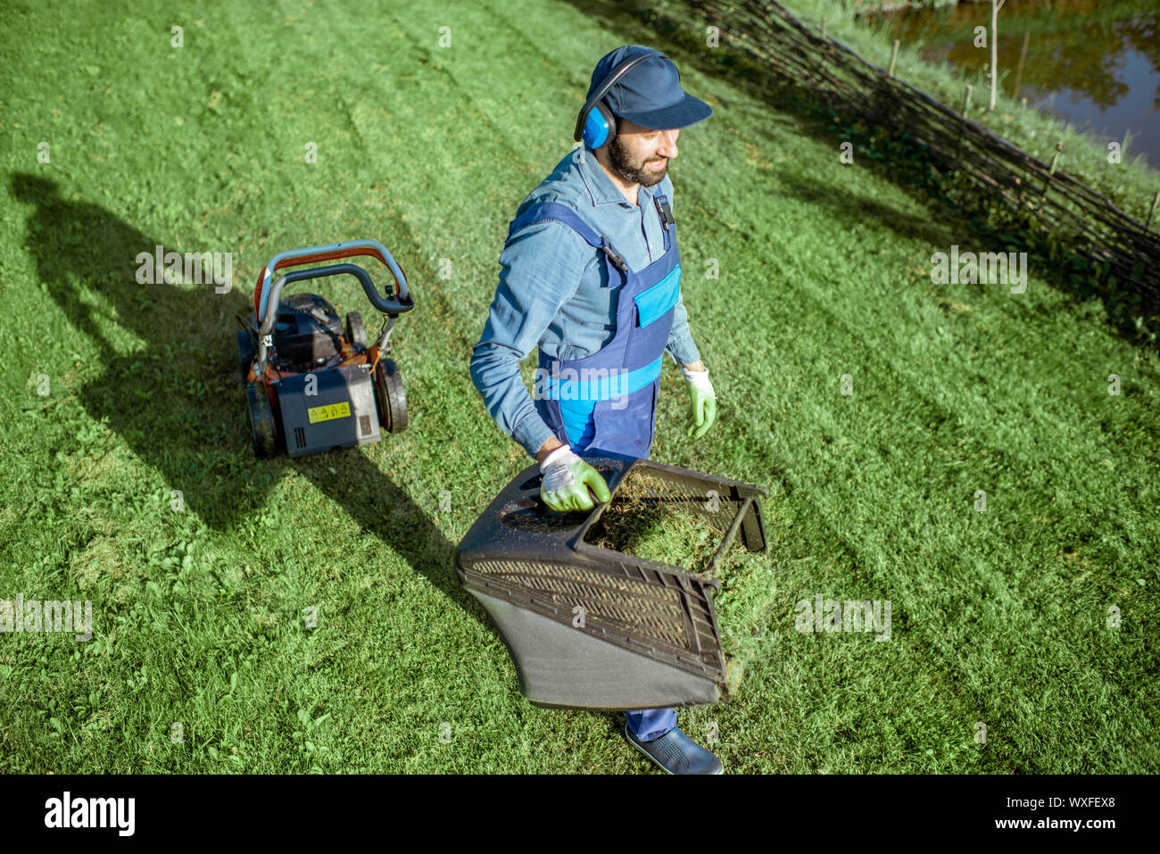 Professional gardener in protective workwear carrying basket full of